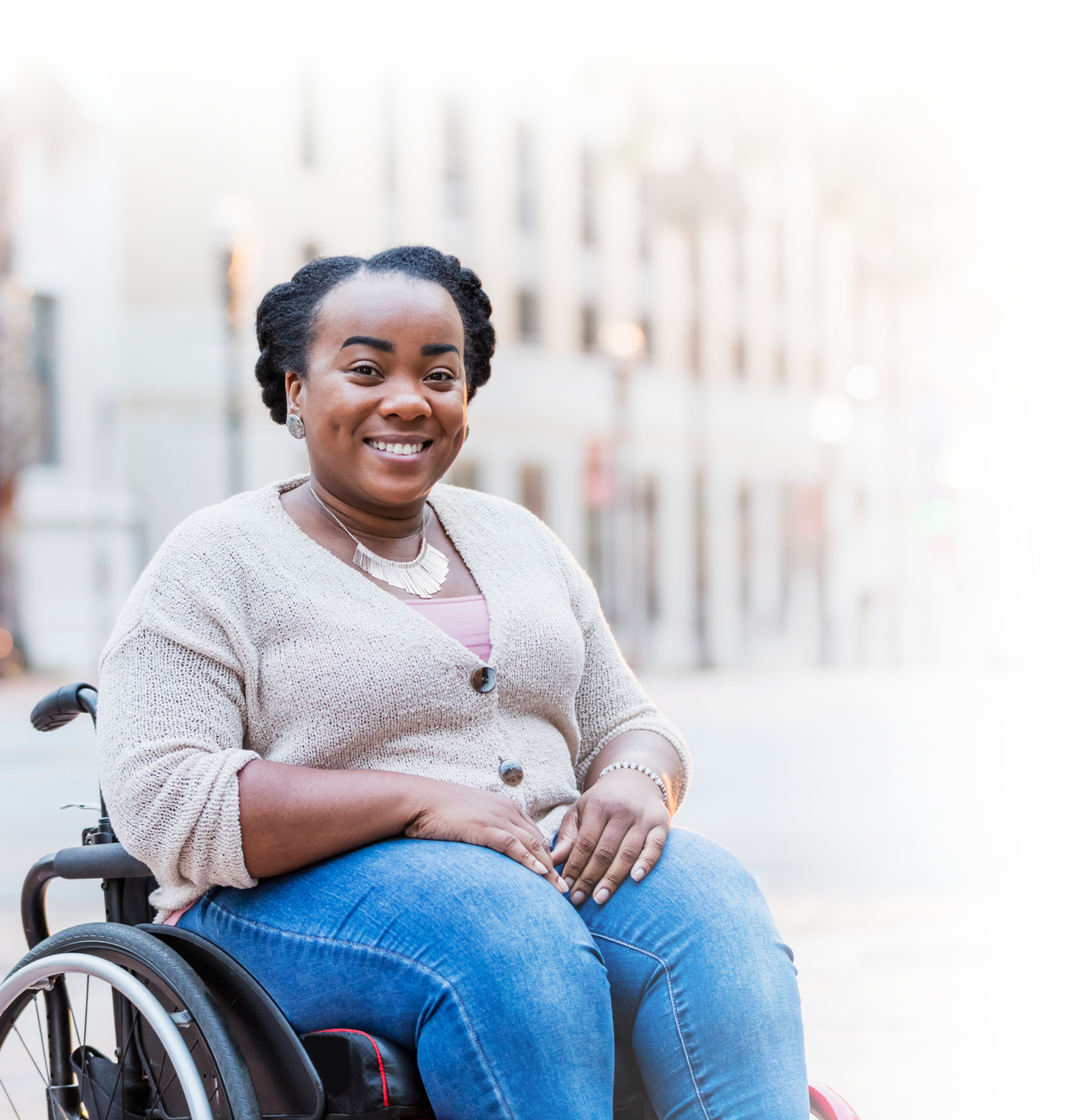 Young woman chair-user, smiling while outside on the city sidewalk.